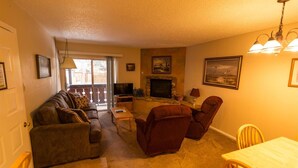 Una sala de estar con sofá, sillas, chimenea, televisor y mesa de comedor.