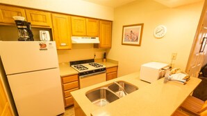 Cocina compacta con refrigerador, estufa, pileta y microondas.