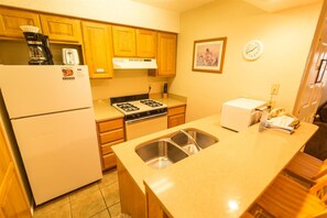 Kitchen features a refrigerator, stove, sink, and wooden cabinets.