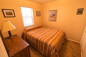 Cozy bedroom with a single bed, nightstand, and framed artwork.