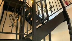 Una escalera en espiral negra con barandales y pasamanos ornamentados, que conduce a un piso superior.