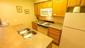 A kitchen with wooden cabinets, a microwave, a stove, a sink, and a refrigerator. - Condo in the mountains! (Red River)