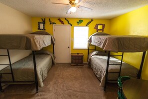 Two comfortable bunk beds with mattresses and blankets, a dresser, and a ceiling fan in a cozy room.