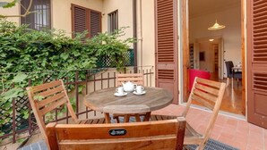 Une table en bois, des chaises et une théière sont disposés sur un balcon d’où l’on peut admirer la vue sur l’intérieur.