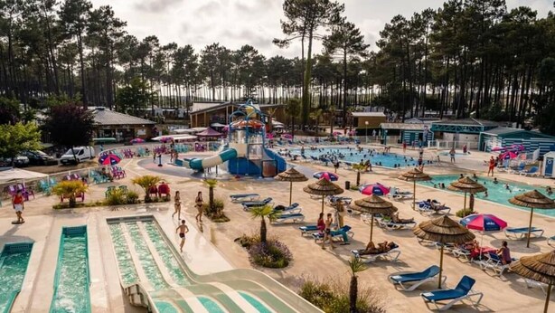 Ein Wasserpark mit mehreren Rutschen und Pools, umgeben von Liegestühlen und Sonnenschirmen.