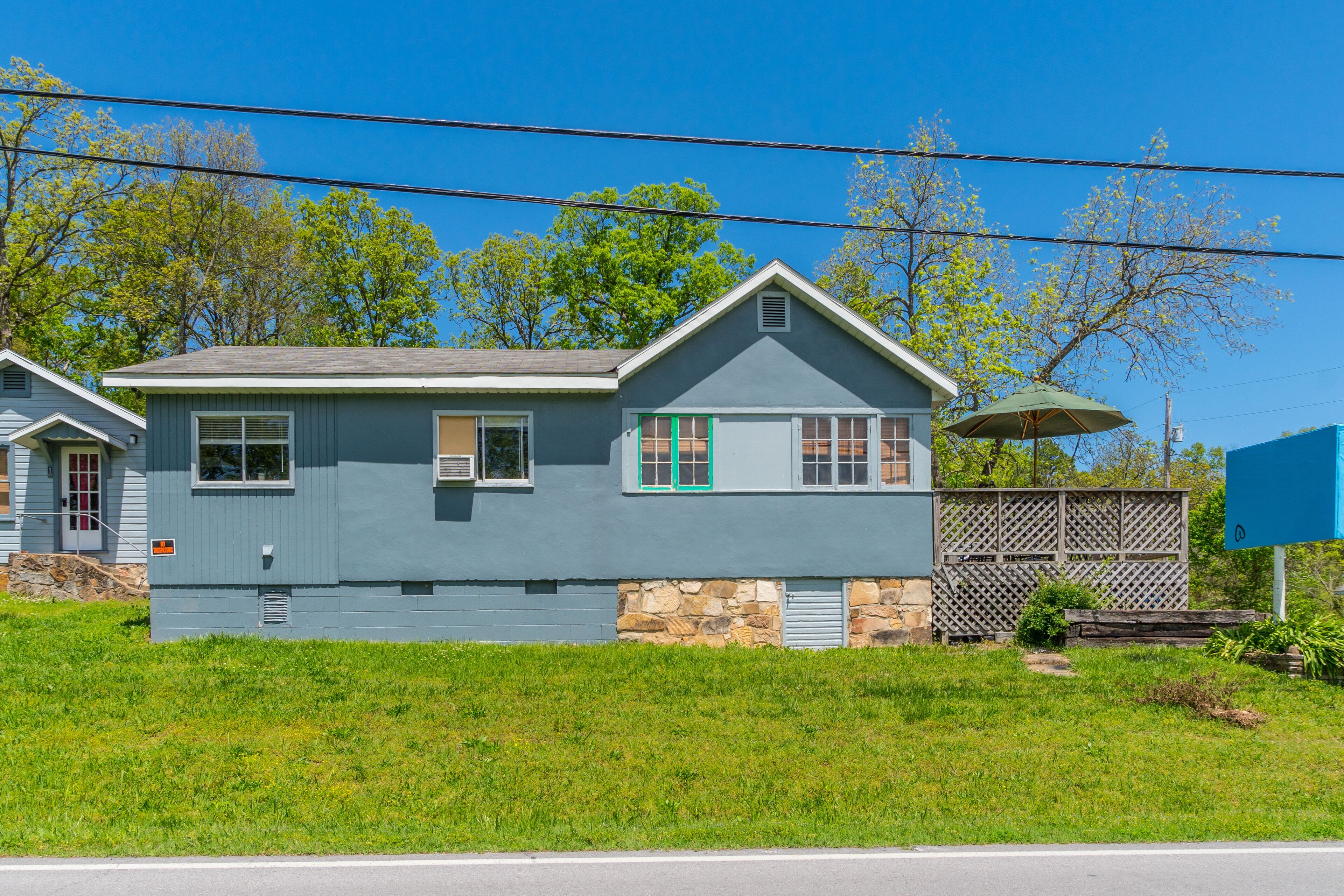 A two-story house with a stone foundation, a sloped roof, and a small porch area.
