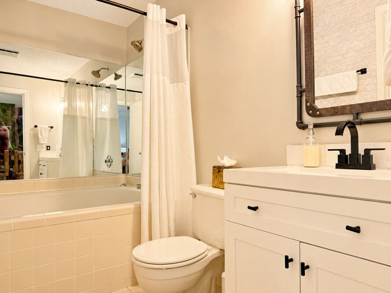 A bathroom with a bathtub, toilet, and a mirror above the sink.
