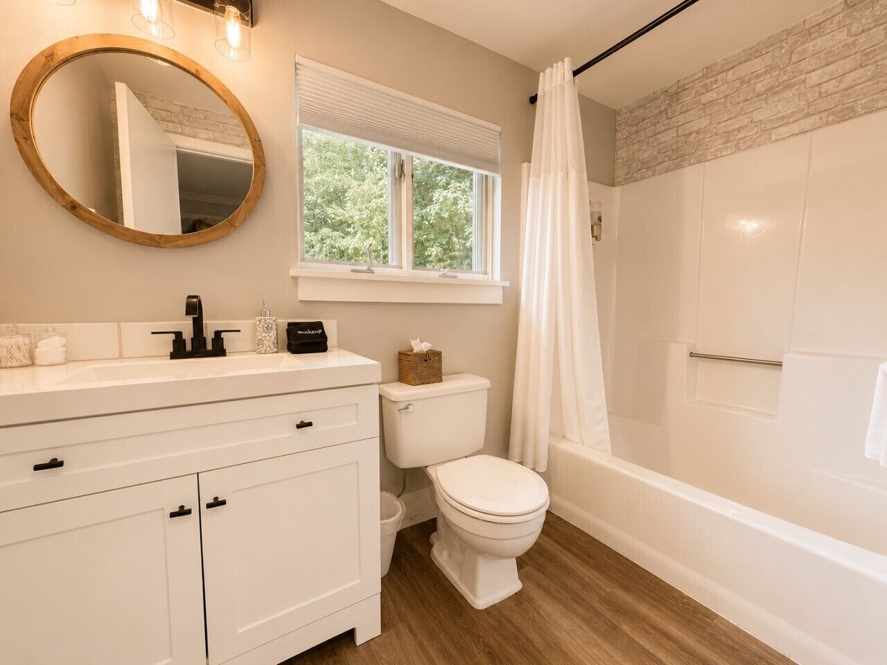 A bathroom with a white vanity, a toilet, a shower with a curtain, and a window with blinds.
