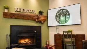 Ett mysigt vardagsrum med en öppen spis, en upphängd skylt med texten ”Killington” och en inramad logotyp för ”Killington Mountain Homes”.