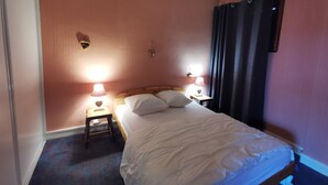A bedroom with a single bed, two bedside lamps, a nightstand, and a wall-mounted lamp.