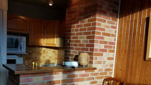A cozy kitchen with a brick wall, wooden cabinets, and a microwave.