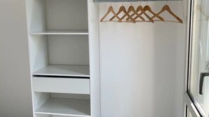 A white closet with multiple shelves and a wooden hanger rod.