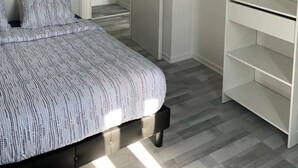 A bedroom with a bed, a wardrobe, and a closet with hangers.