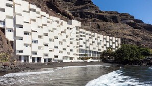 Ein Küstenhotel mit weißer Fassade, mehreren Balkonen und Meerblick.