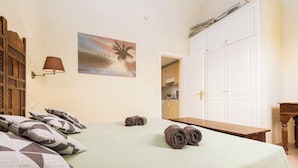 A hotel room with a bed, pillows, a painting, a lamp, and a wardrobe. - Home2Book Oasis Paradise Home Fuerteventura (Corralejo)