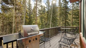 En terrasse med en Char-Broil grill, metal stole og borde.