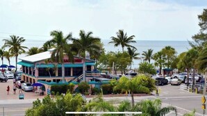 Un hotel frente al mar con una estructura de dos pisos, palmeras y vista al océano.