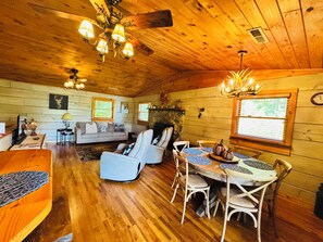 A cozy cabin interior with a dining area, sofa, and fireplace.