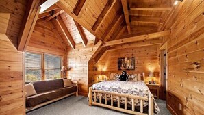 Camera da letto accogliente in legno con un letto a soppalco, una panca e una finestra con persiane.