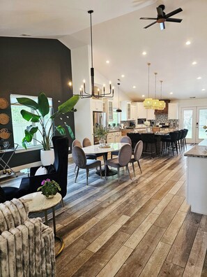 Una cocina moderna con armarios blancos, una isla central y un comedor con una mesa redonda y sillas.