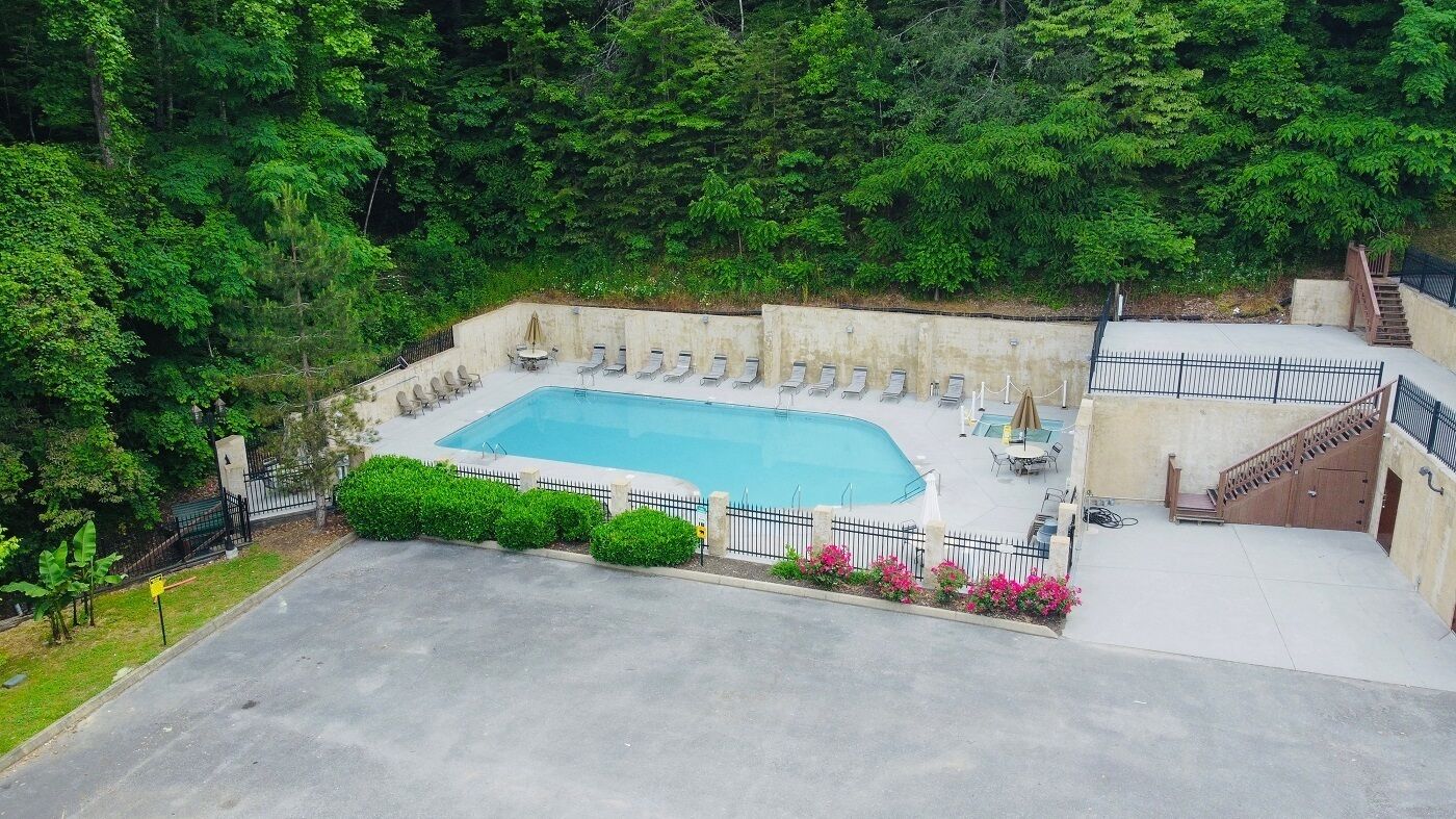 A rectangular swimming pool surrounded by lounge chairs, a staircase, and a concrete deck.