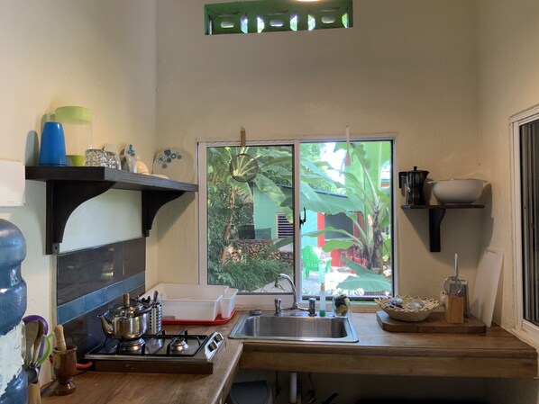 A kitchen with a gas stove, sink, and a window overlooking a garden.