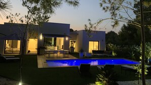 A modern house with a swimming pool, outdoor seating, and a well-lit patio area. - Villa Acacia (Las Colinas Golf) (Orihuela Costa)