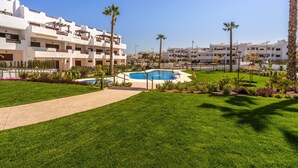 Ein Hotel mit Schwimmbad, Palmen und einem gepflegten Rasen.