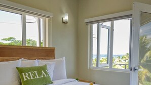 Et hotelværelse med seng, et vindue med udsigt og et bakke med en flaske, blomster samt et glas appelsinjuice.