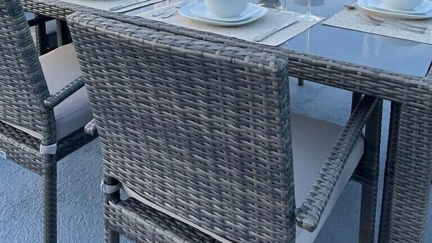 Et spisebord med udsigt til havet, fletstole og en klar himmel.