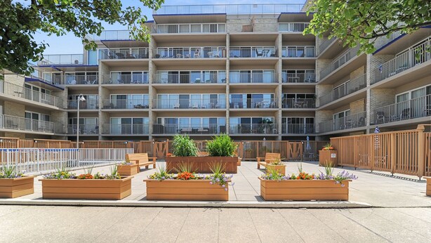 Un edificio de varios pisos con balcones, mobiliario exterior y macetas.
