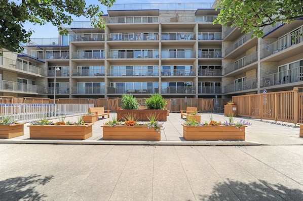 A multi-story building with balconies, outdoor seating, and planters.