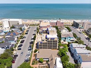 An aerial view of a coastal town with a beach, residential buildings, and a parking lot. - Steps to Beach Downtown Rehoboth Beach Efficiency Pool Parking (Rehoboth Beach)