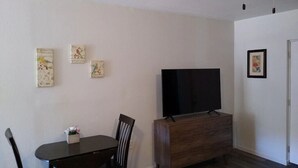 A dining area with a wooden table and chairs, a television on a wooden cabinet, and three wall-mounted pictures. - Groveport Resort/Waterfront Cabin C/Newly Remodeled (Grove)