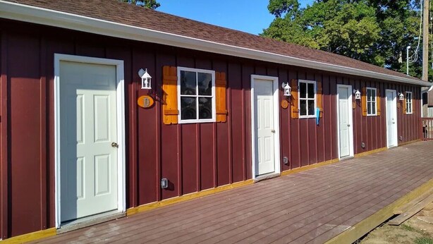 A row of red wooden cabins with white doors and windows, each with a small porch. - Groveport Resort/Waterfront Cabin C/Newly Remodeled (Grove)