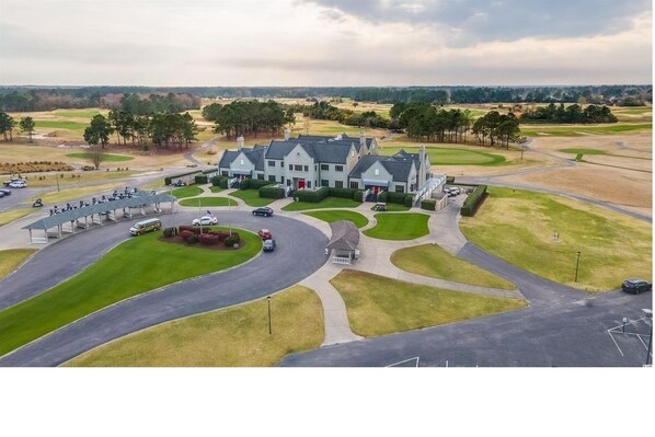 A large, multi-story building with a symmetrical facade, surrounded by well-maintained lawns and a golf course in the background. - Relaxing 3-Bedroom Condo Overlooking Golf Course (Myrtle Beach)