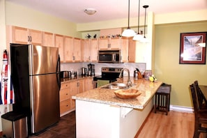 Kitchen features stainless steel appliances, a granite countertop, and a small island with a sink.