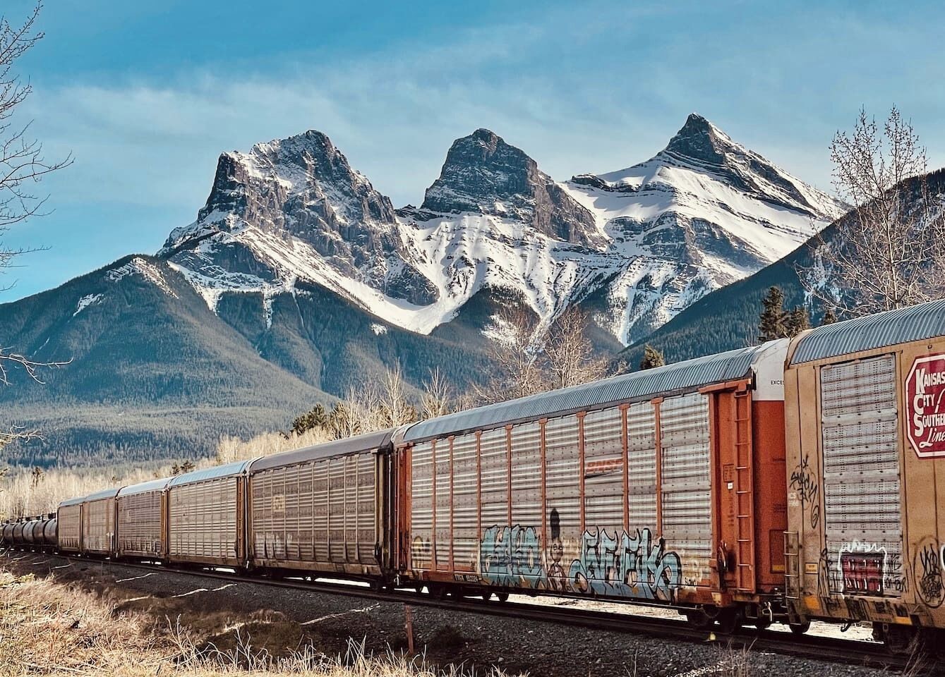 A freight train with cargo cars passing through a mountainous area.