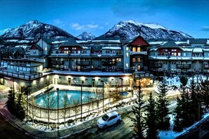A large resort with multiple buildings, a swimming pool, and a mountainous backdrop.