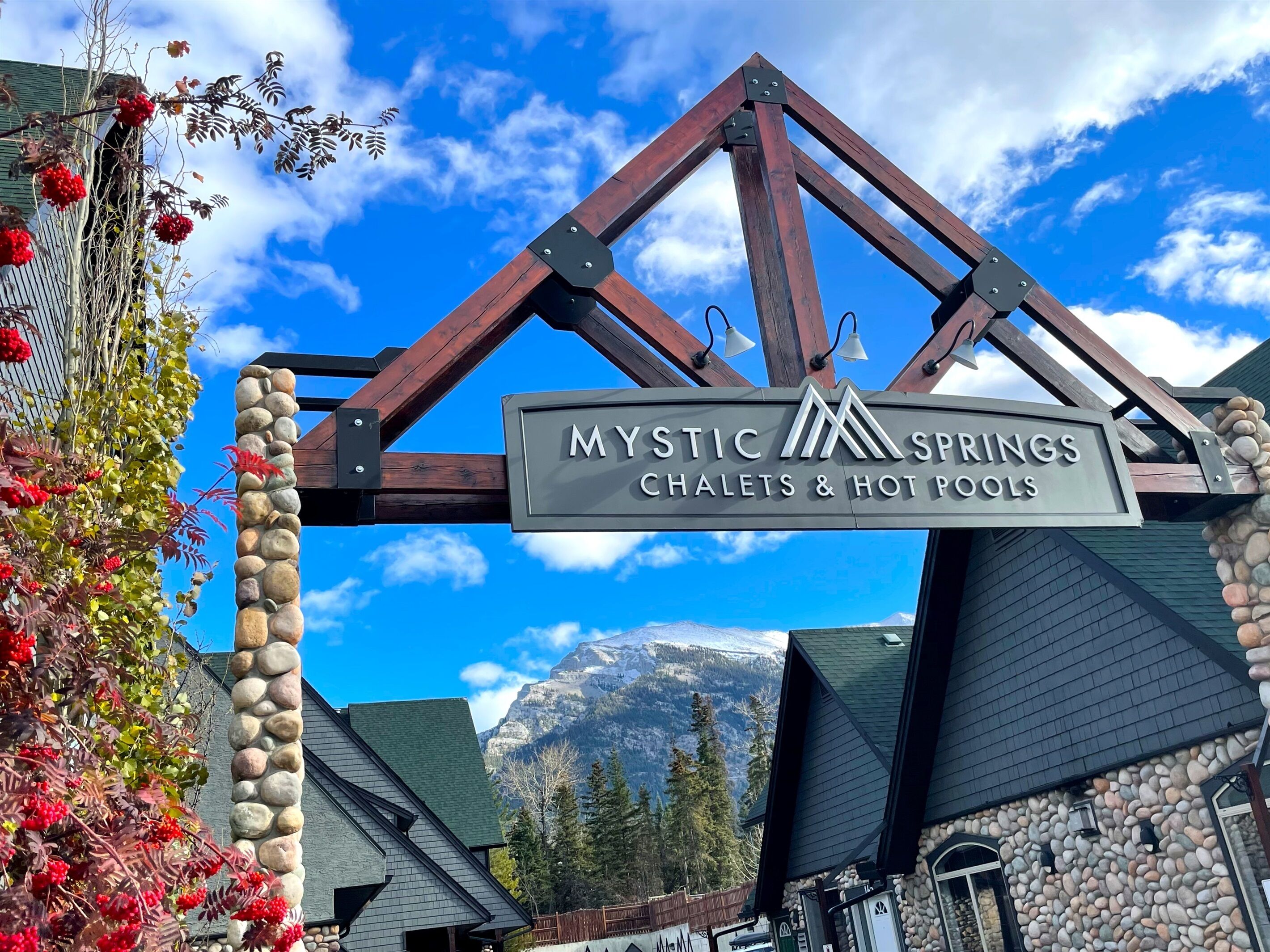 A sign for Mystic Springs Chalets & Hot Pools with a mountainous backdrop.