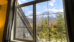 A window with a view of snow-capped mountains and trees. - 🥇Renovated Chalet at Mystic Springs, Pool, Hot Tub! (Canmore)