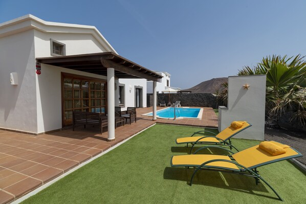 A modern villa with a swimming pool, outdoor seating, and a patio area.