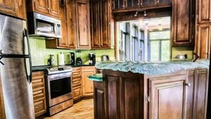 A kitchen with wooden cabinets, a stainless steel refrigerator, an oven, and a microwave. - Chalet cheri (Mont-Tremblant)