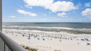 A beach with umbrellas and beach chairs, a clear sky, and the ocean.