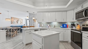 A modern kitchen with white cabinetry, a central island, and stainless steel appliances.