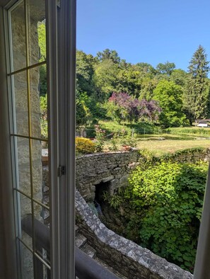 A stone bridge over a water feature, lush greenery, and a clear blue sky.