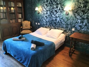Un dormitorio con cama, una silla, una mesa de madera y una estantería.