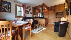 Een gezellig cabin interieur met een eethoek, een bank, houten kasten en een keuken.