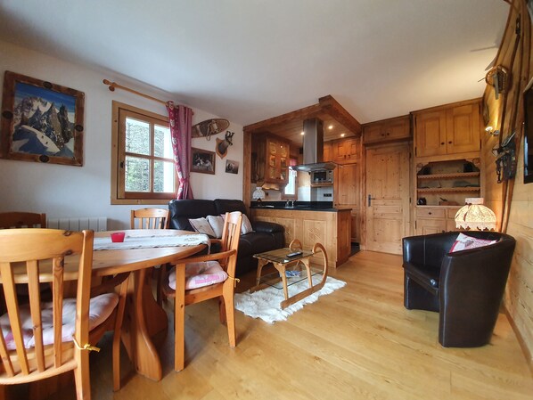 A cozy cabin interior with a dining area, a sofa, wooden cabinets, and a kitchen.