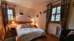 Een knus slaapkamer met een houten bed, twee bedlampjes, een radiator en een raam met gordijnen.